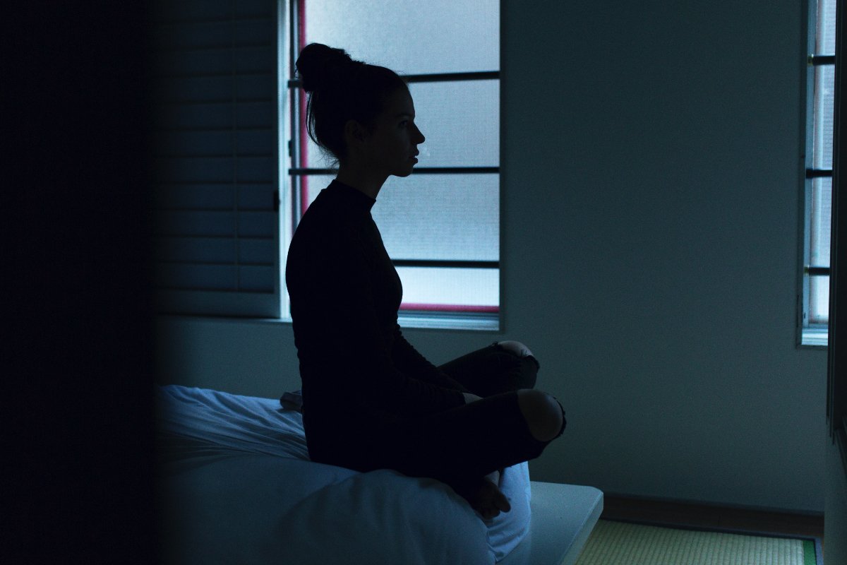photograph of a woman sitting on the edge of a bed by ben blenner hasset unsplash